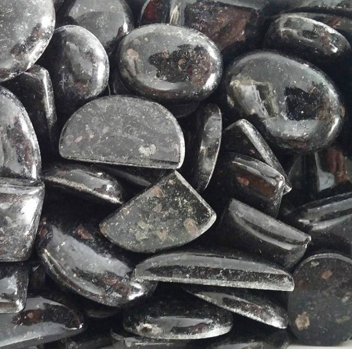 Polished nuummite cabochon showing dark iridescent flash